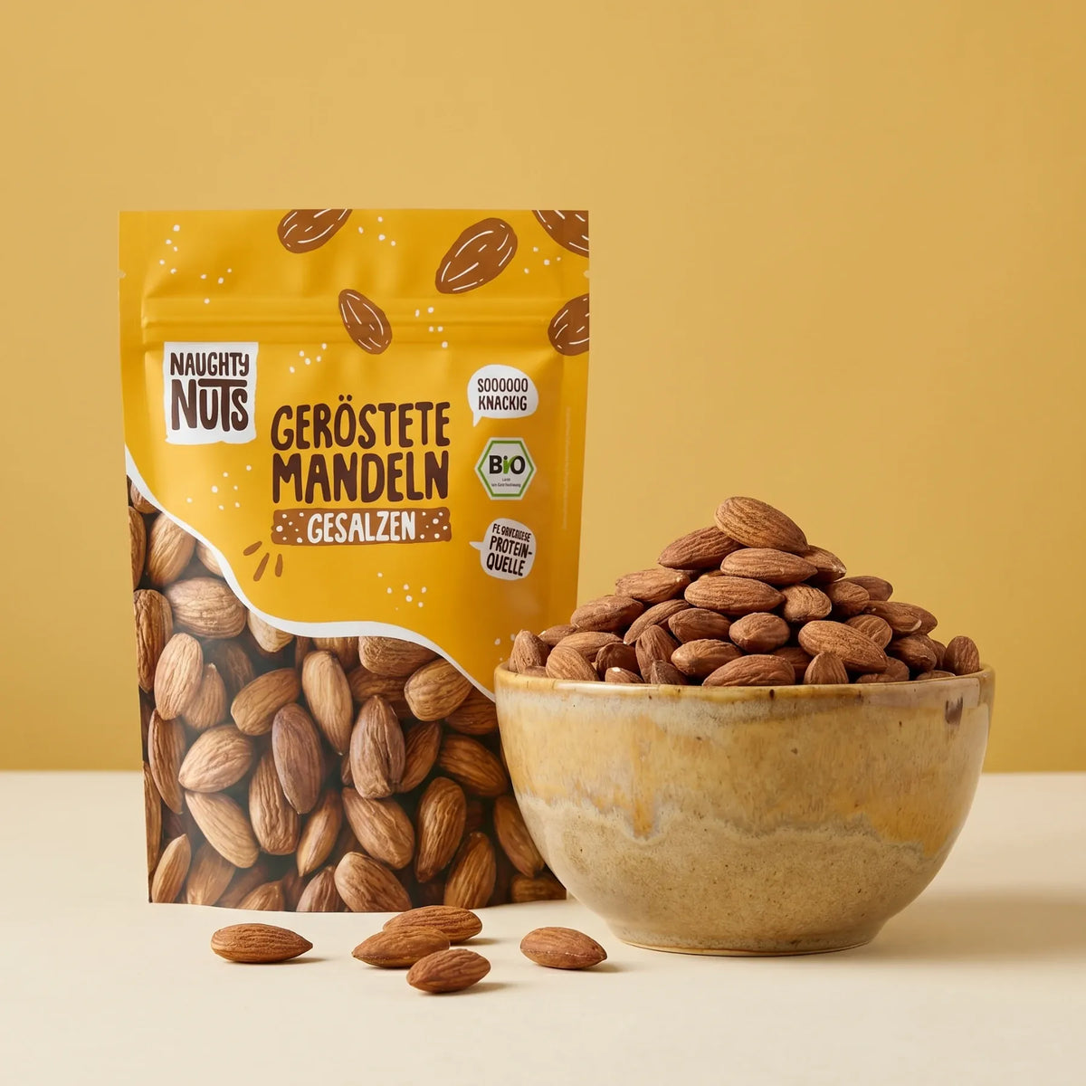 Naughty Nuts geröstete Mandeln gesalzen Packung und Schale mit Mandeln