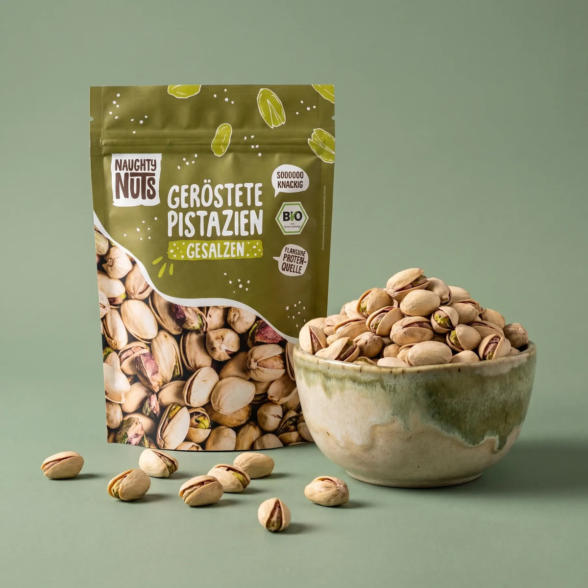 Naughty Nuts geröstete und gesalzene Pistazien in einer Packung und einer Schale